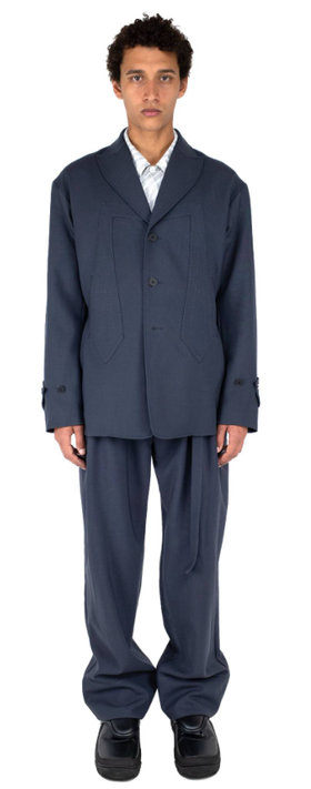 A man wearing a dark navy Kiko Kostadinov suit