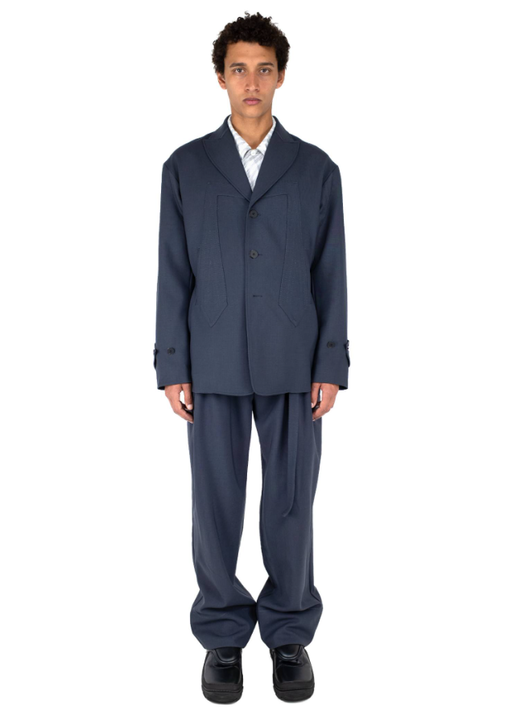 A man wearing a dark navy Kiko Kostadinov suit