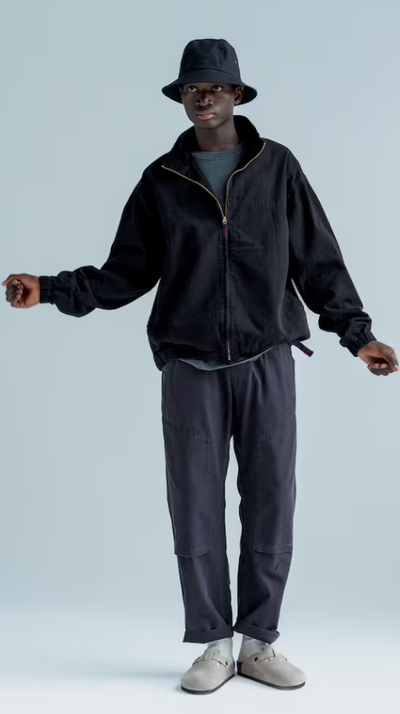 A man wearing a gramicci black fleece and a bucket hat