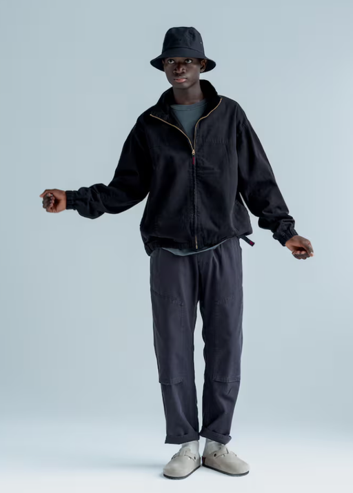 A man wearing a gramicci black fleece and a bucket hat