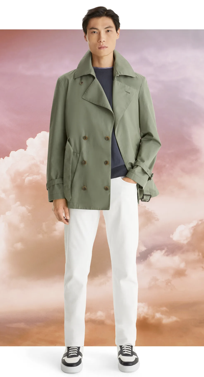 A man wearing a olive green Canali jacket with white pants and sneakers