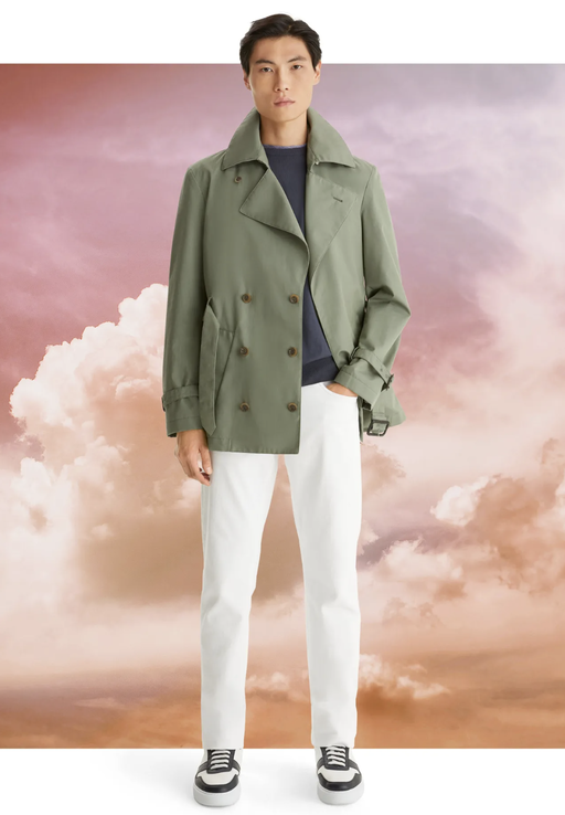 A man wearing a olive green Canali jacket with white pants and sneakers