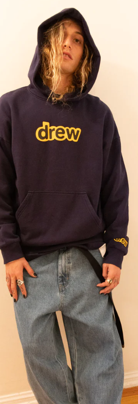 A man wearing a drew house hoodie in navy blue and yellow