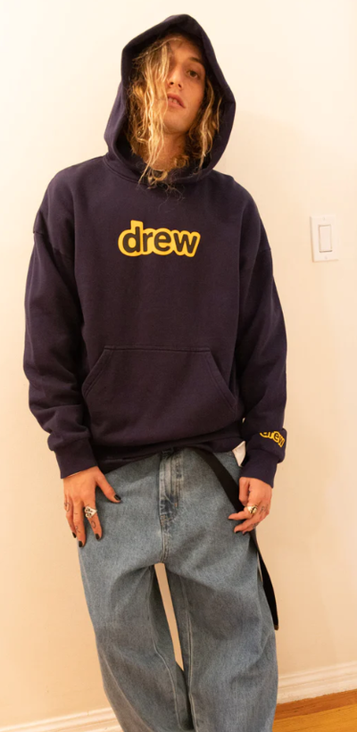 A man wearing a drew house hoodie in navy blue and yellow