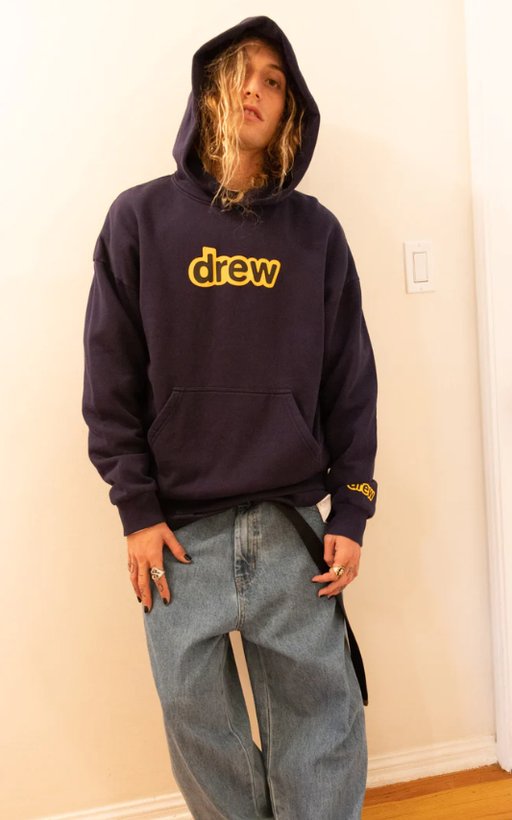 A man wearing a drew house hoodie in navy blue and yellow