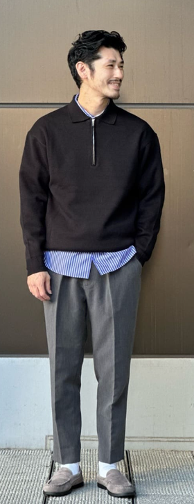 A man wearing a United Arrows black long-sleeve and grey pants
