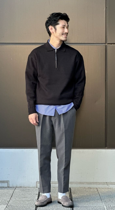 A man wearing a United Arrows black long-sleeve and grey pants
