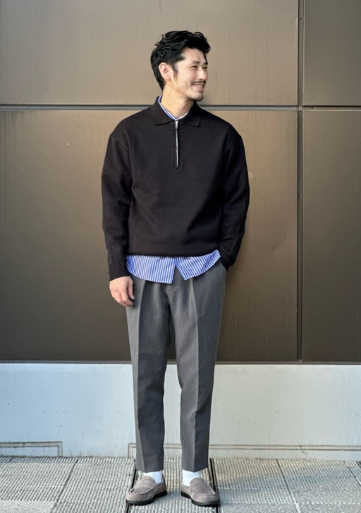 A man wearing a United Arrows black long-sleeve and grey pants