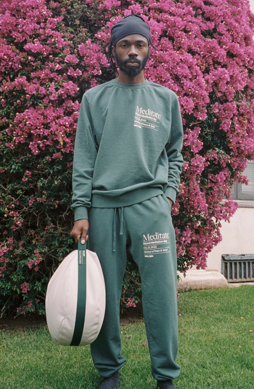 A man wearing a green MUSEUM OF PEACE AND QUIET sweatsuit