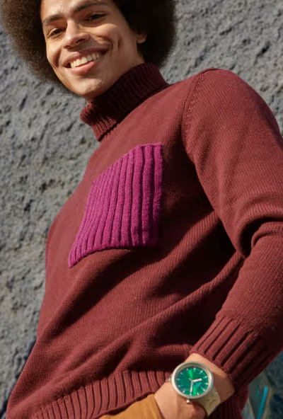 A man wearing a silver Swatch and a turtle-neck long-sleeve