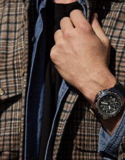 A man wearing a black Citizen Watch and a plaid jacket