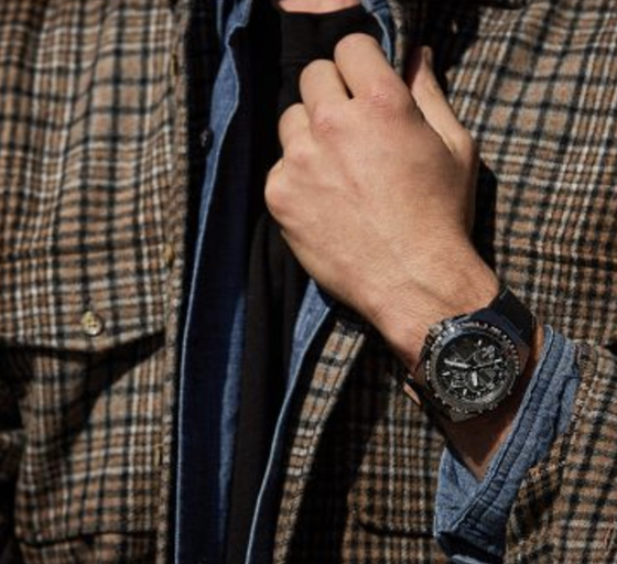 A man wearing a black Citizen Watch and a plaid jacket
