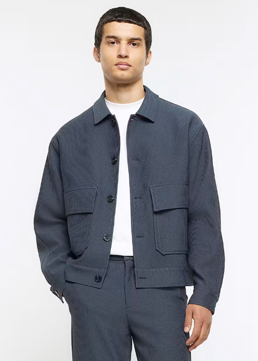 A man wearing a River Island jacket and a white t-shirt