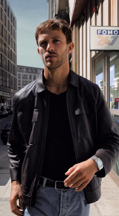 A man wearing a Tissot silver watch and a black jacket