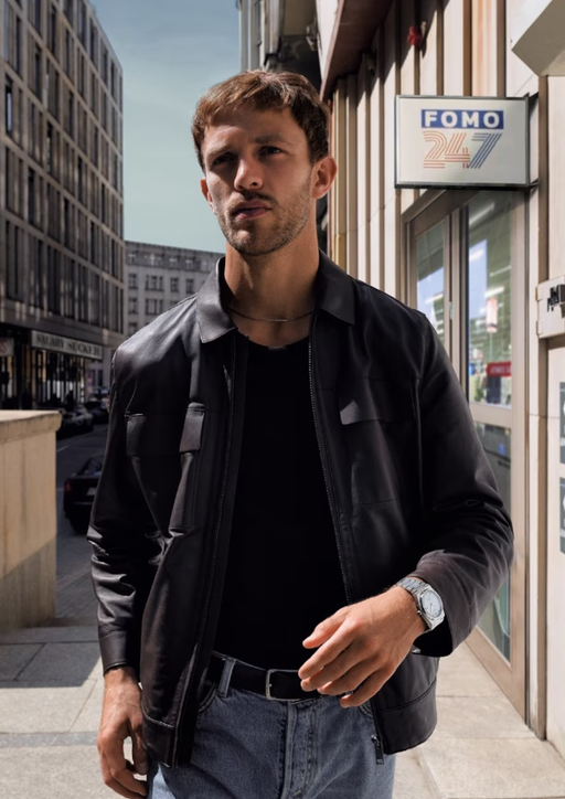 A man wearing a Tissot silver watch and a black jacket