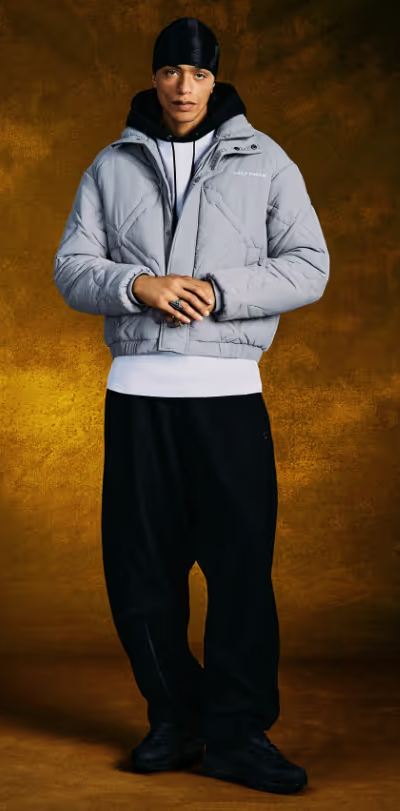 A man wearing a Daily Paper outfit with a grey jacket and white shirt