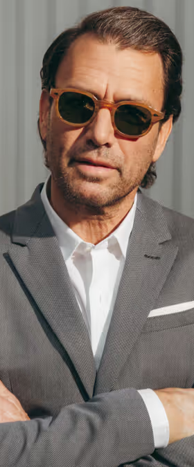 A man wearing a pair of Moscot sunglasses and a grey suit