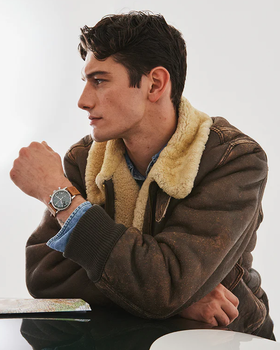 A man wearing a silver Timex and a brown jacket