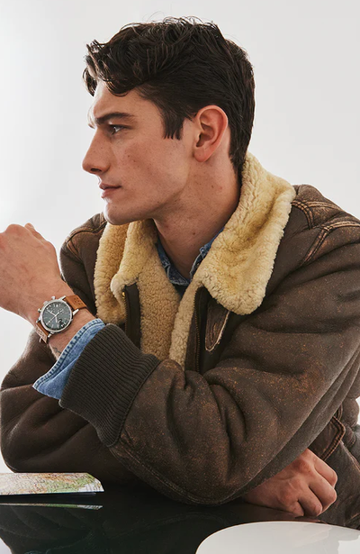 A man wearing a silver Timex and a brown jacket