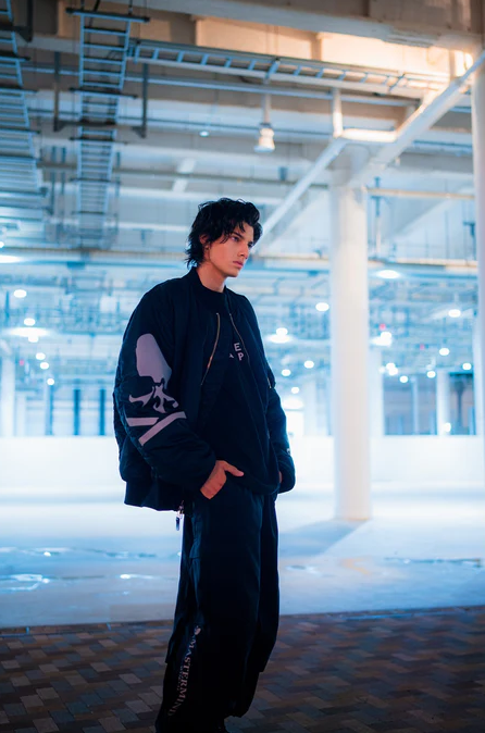 A man wearing a black skulls Mastermind jacket