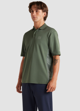 A man wearing a Manors Golf green polo and black pants