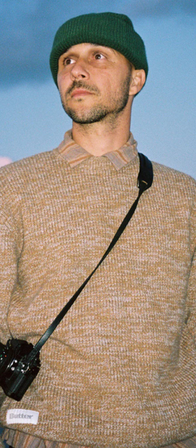 A man wearing a BUTTER GOODS outfit in brown with a camera