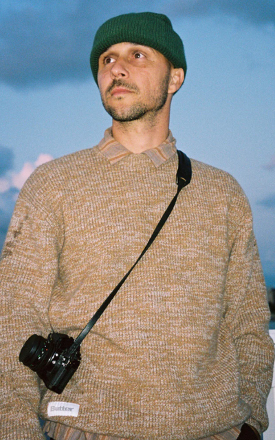 A man wearing a BUTTER GOODS outfit in brown with a camera