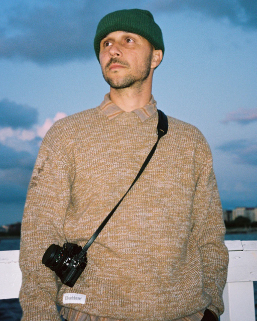 A man wearing a BUTTER GOODS outfit in brown with a camera