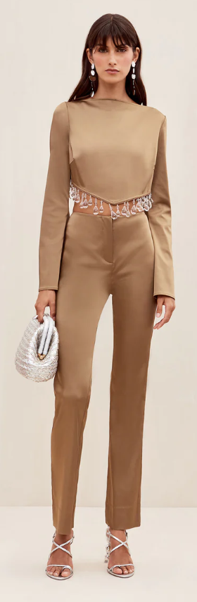 A woman wearing a brown Cult Gaia formal outfit with a white purse
