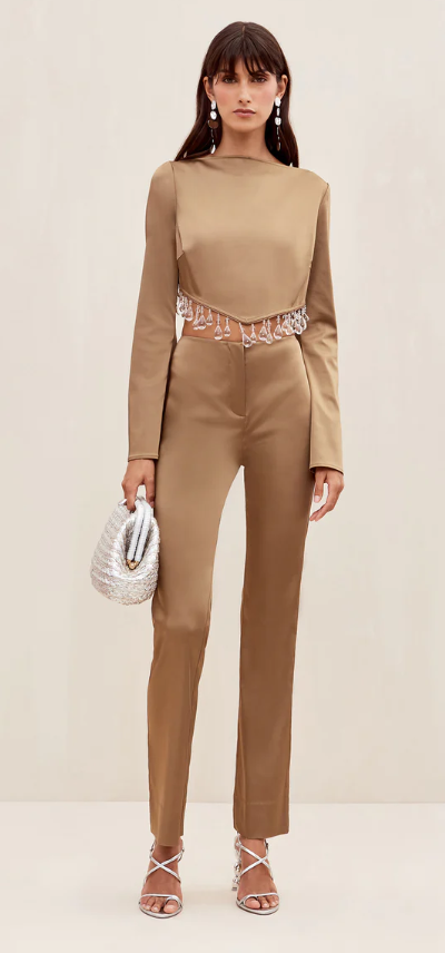 A woman wearing a brown Cult Gaia formal outfit with a white purse