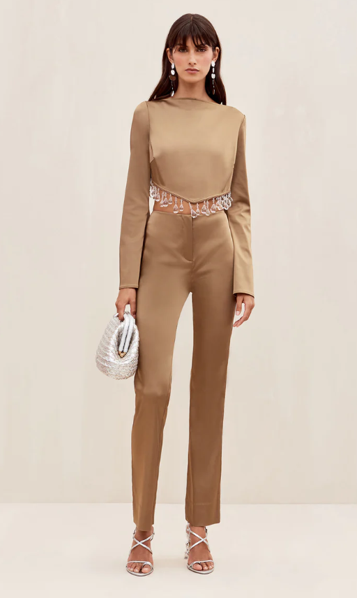 A woman wearing a brown Cult Gaia formal outfit with a white purse