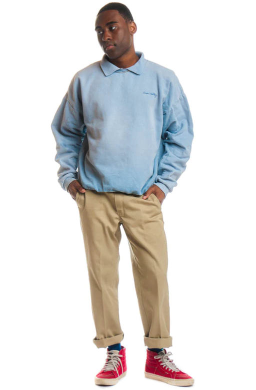 A man wearing a Tunnel Vision powder blue long-sleeve and brown chinos