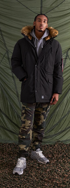 A man wearing an Alpha Industries jacket and camo pants