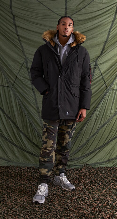 A man wearing an Alpha Industries jacket and camo pants