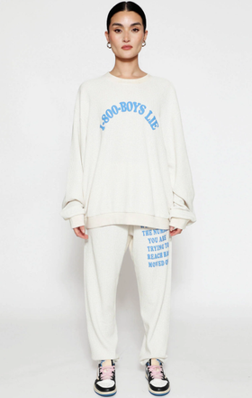 A woman wearing a Boys Lie cream suit and blue text
