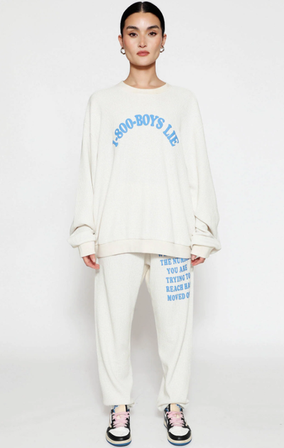 A woman wearing a Boys Lie cream suit and blue text