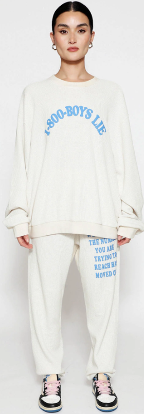 A woman wearing a Boys Lie cream suit and blue text