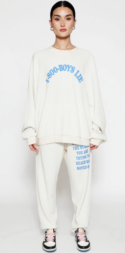 A woman wearing a Boys Lie cream suit and blue text