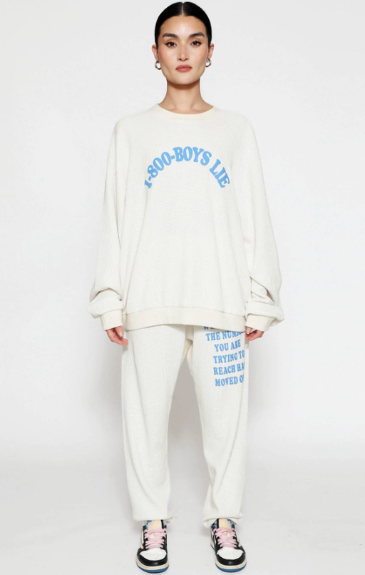 A woman wearing a Boys Lie cream suit and blue text