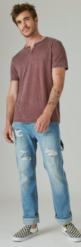 A man wearing a red-washed Lucky Brand t-shirt and blue jeans