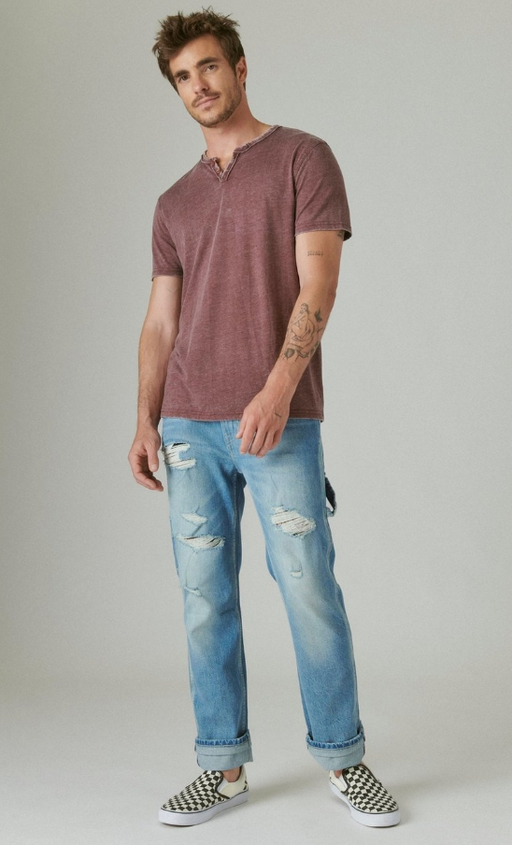 A man wearing a red-washed Lucky Brand t-shirt and blue jeans