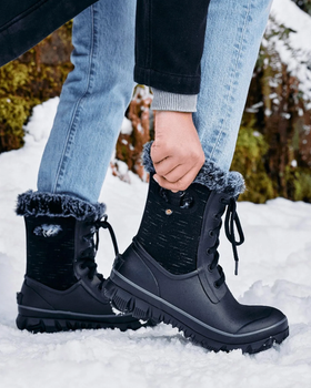A woman wearing a pair of black Bogs Boots in the snow