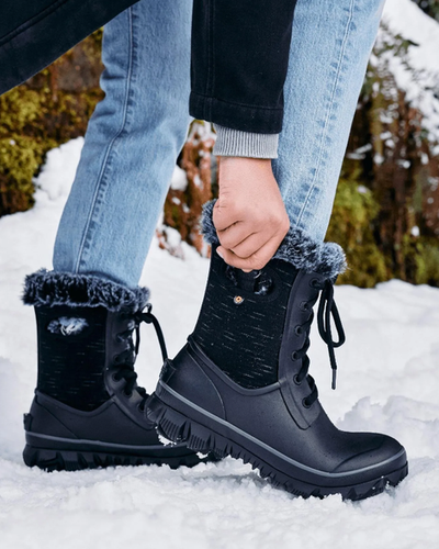 A woman wearing a pair of black Bogs Boots in the snow