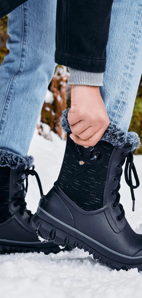 A woman wearing a pair of black Bogs Boots in the snow
