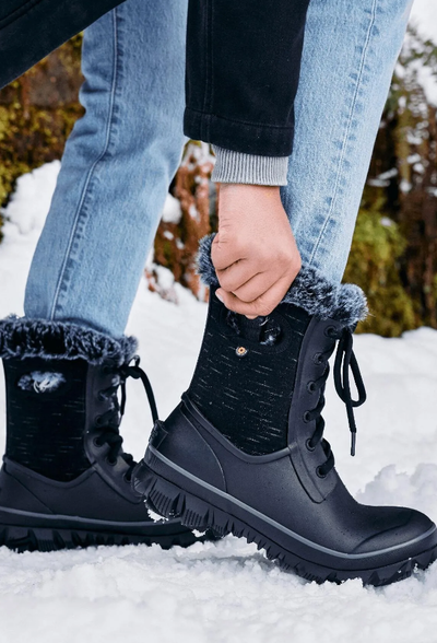 A woman wearing a pair of black Bogs Boots in the snow