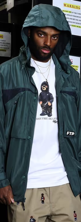 A man wearing a FTP outfit featuring a white t-shirt and blue rain coat