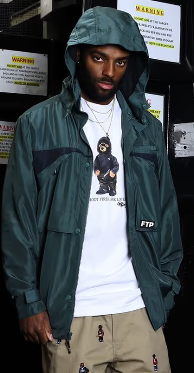 A man wearing a FTP outfit featuring a white t-shirt and blue rain coat