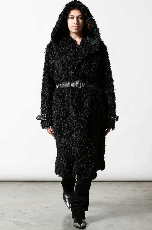 A man wearing an all-black Sourpuss outfit with black boots
