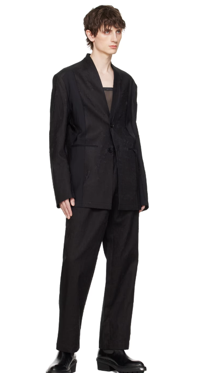 A man wearing a Feng Chen Wang black distressed blazer