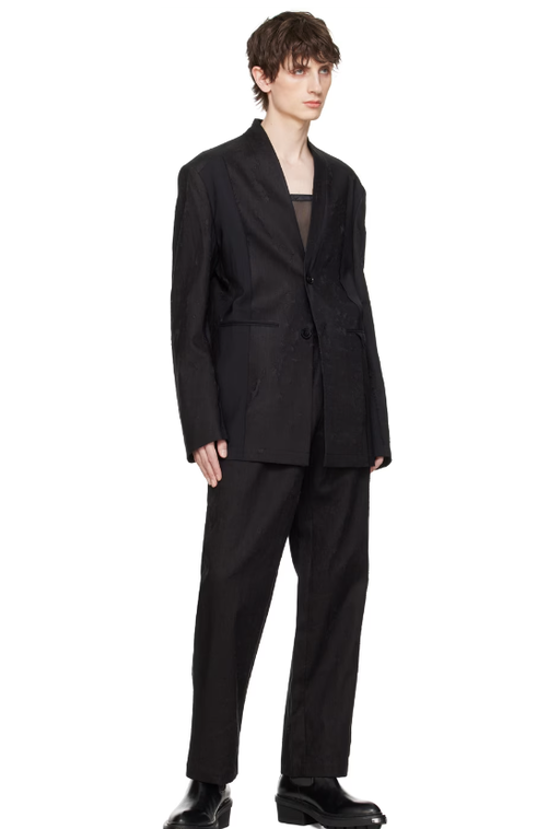 A man wearing a Feng Chen Wang black distressed blazer